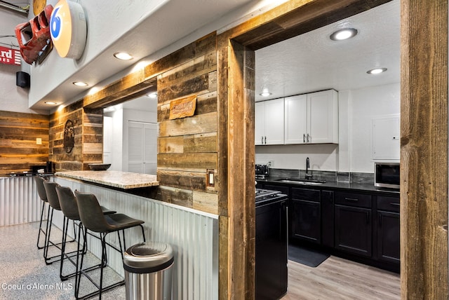 1715 Sherman Ave, Coeur Dalene, ID 83814 - bar with white cabinetry, sink, light hardwood / wood-style floors, and a textured ceiling