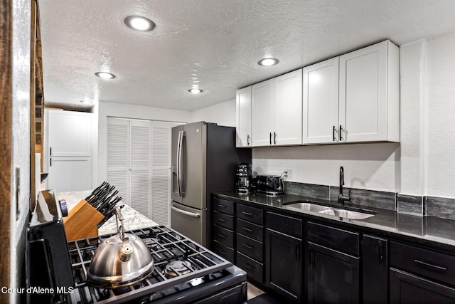 1715 Sherman Ave, Coeur Dalene, ID 83814 - kitchen with white cabinetry, sink, dark stone countertops, and stainless steel fridge