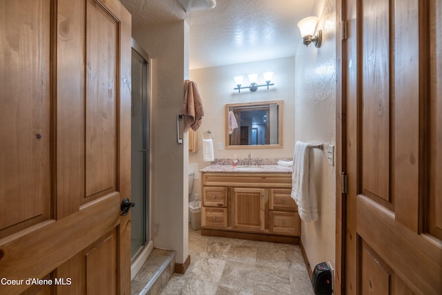 bathroom with walk in shower, vanity, toilet, and a textured ceiling