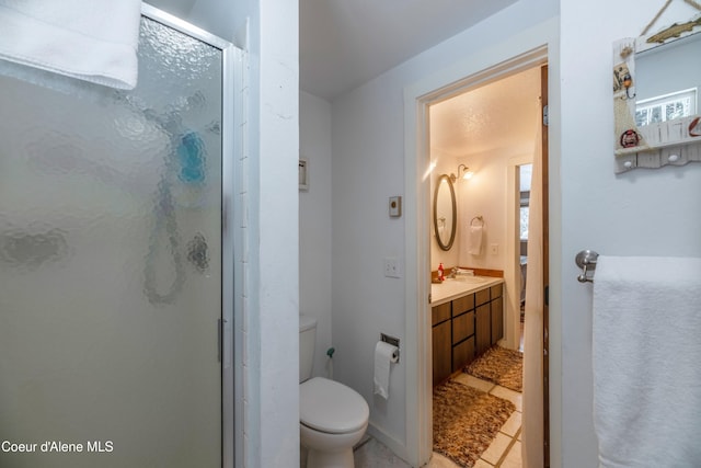 bathroom featuring tile patterned flooring, vanity, toilet, and walk in shower