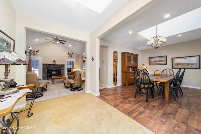 dining room featuring recessed lighting, dark wood finished floors, lofted ceiling, a fireplace, and ceiling fan with notable chandelier