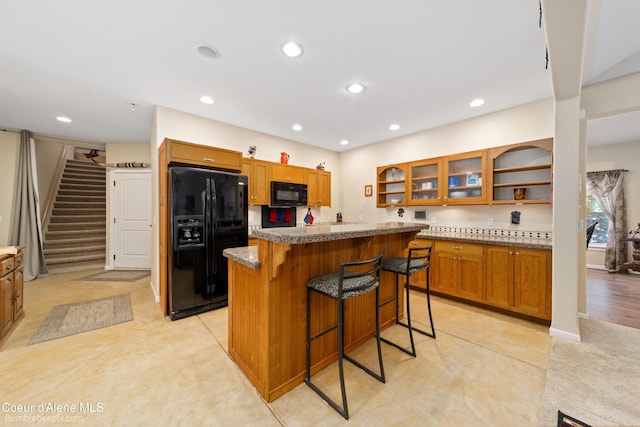 kitchen featuring open shelves, a center island, brown cabinets, black appliances, and glass insert cabinets