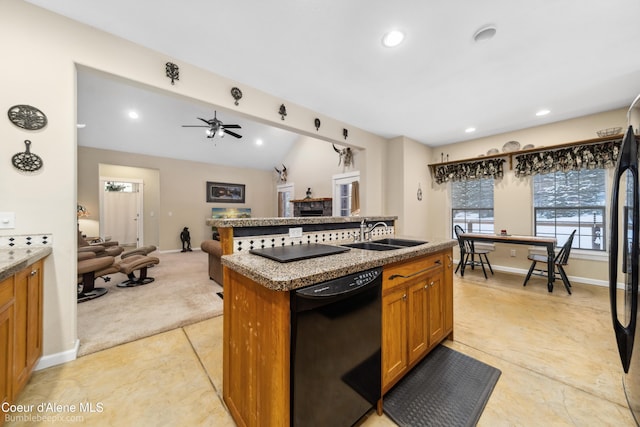 kitchen with brown cabinets, open floor plan, a kitchen island with sink, black appliances, and a sink