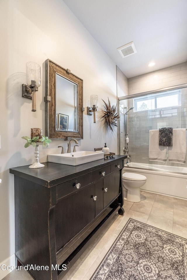 bathroom with visible vents, toilet, combined bath / shower with glass door, vanity, and tile patterned floors