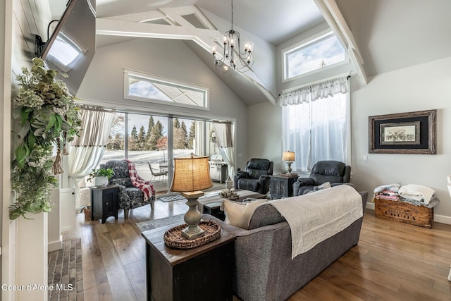 living room with high vaulted ceiling, baseboards, a notable chandelier, and hardwood / wood-style floors