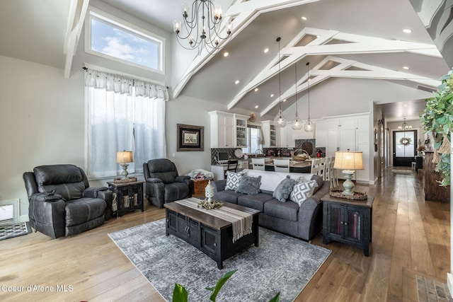 living area with high vaulted ceiling, visible vents, light wood-style flooring, and an inviting chandelier