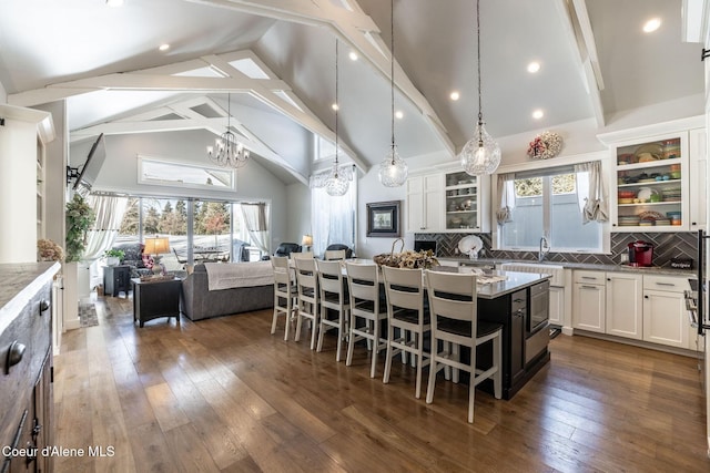 kitchen with dark wood finished floors, white cabinetry, open floor plan, backsplash, and a kitchen bar