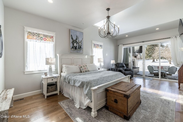 bedroom featuring baseboards, lofted ceiling, wood finished floors, access to exterior, and an inviting chandelier