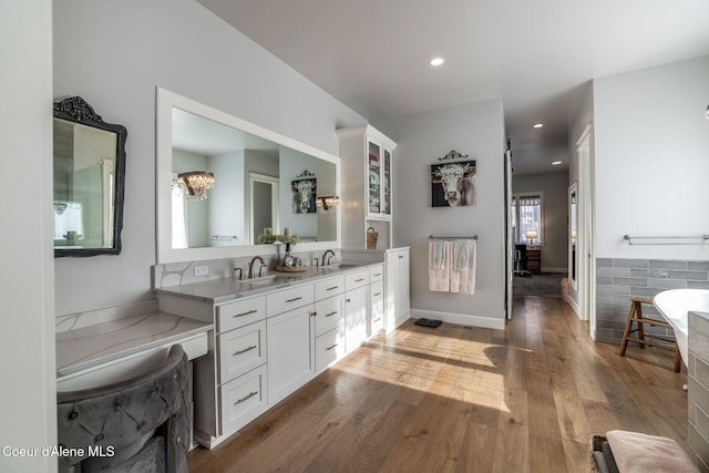 bathroom featuring double vanity, recessed lighting, a sink, wood finished floors, and baseboards