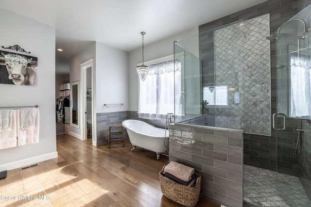 bathroom featuring tile walls, a soaking tub, visible vents, a stall shower, and wood finished floors