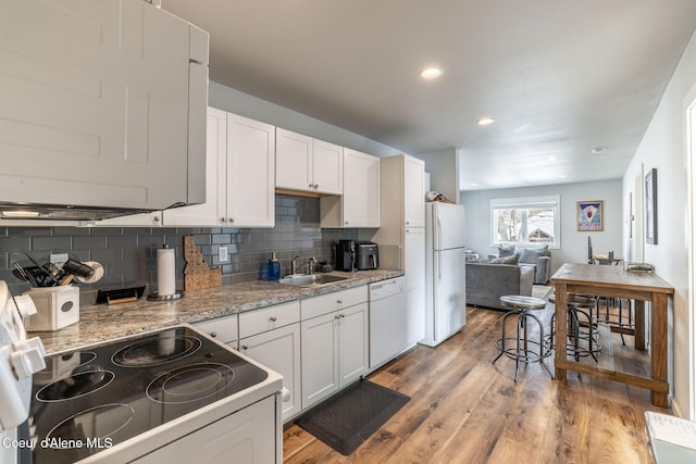 kitchen featuring white appliances, a sink, white cabinets, light wood-type flooring, and tasteful backsplash