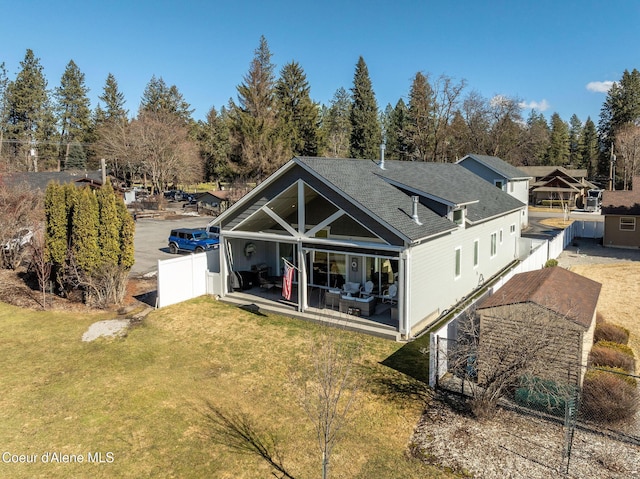 rear view of property with a shingled roof, fence private yard, a patio area, and a yard