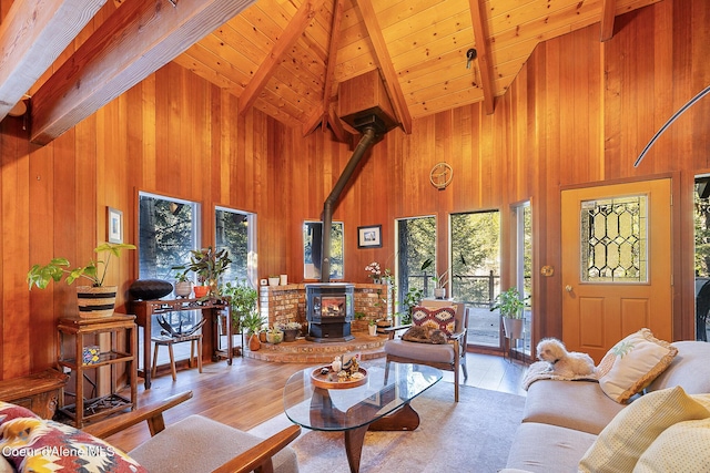 living room featuring light hardwood / wood-style flooring, vaulted ceiling with beams, a wood stove, wooden ceiling, and wooden walls