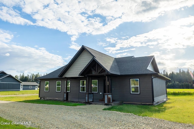 view of front of home with central AC unit, a front lawn, and roof with shingles