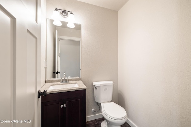 half bath featuring baseboards, vanity, and toilet