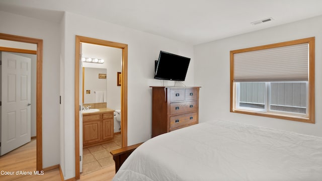 bedroom with sink, light wood-type flooring, and ensuite bath