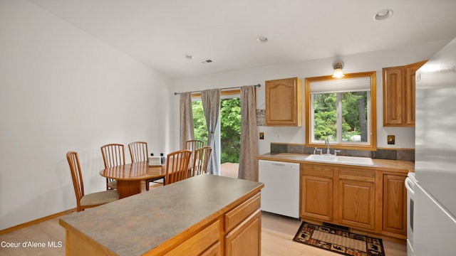 kitchen with a healthy amount of sunlight, sink, white dishwasher, and light wood-type flooring