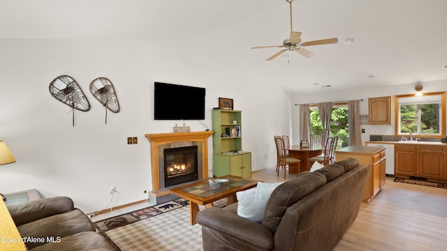 living room featuring ceiling fan, high vaulted ceiling, sink, and light wood-type flooring