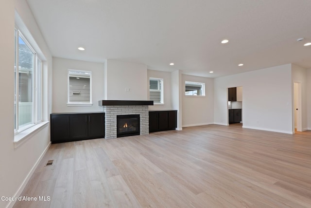 unfurnished living room featuring a fireplace and light hardwood / wood-style flooring