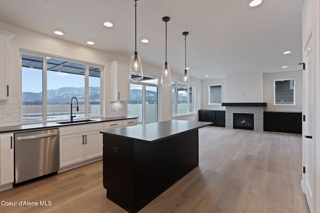 kitchen featuring a kitchen island, sink, hanging light fixtures, stainless steel dishwasher, and a mountain view