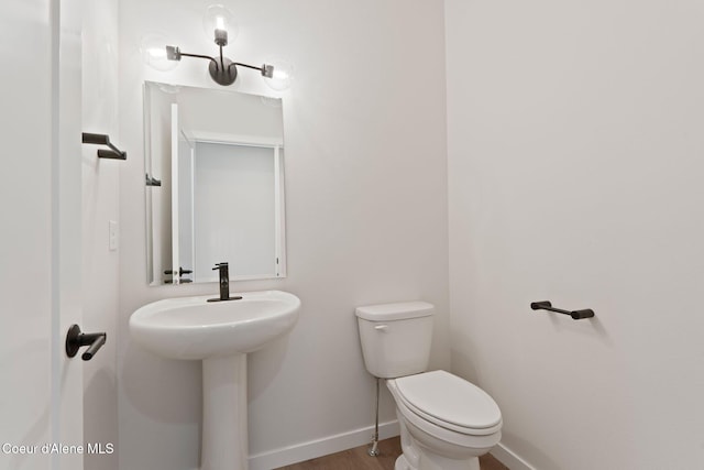 bathroom featuring toilet, sink, and hardwood / wood-style floors