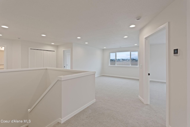 hall featuring light colored carpet and a textured ceiling