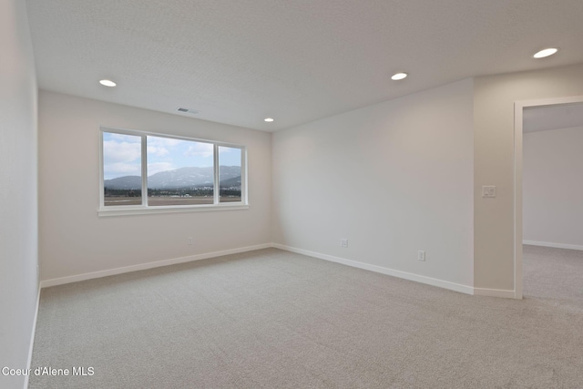 carpeted empty room with a mountain view and a textured ceiling