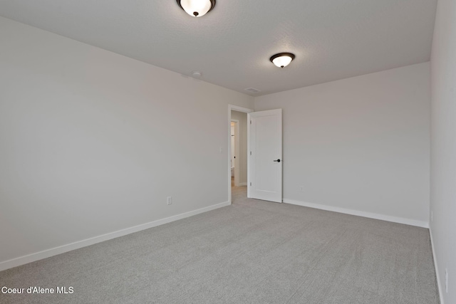 unfurnished room with light colored carpet and a textured ceiling