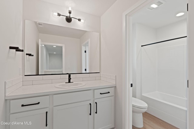 full bathroom featuring hardwood / wood-style flooring, vanity, toilet, and shower / washtub combination