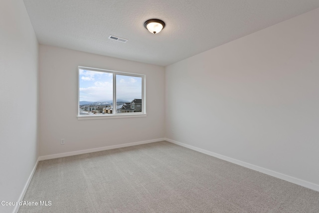 carpeted empty room with a textured ceiling