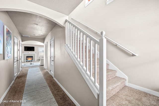 staircase featuring carpet floors and a textured ceiling