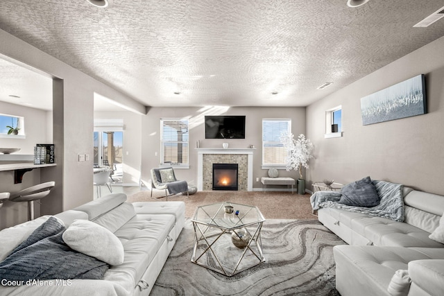 carpeted living room featuring a textured ceiling and a fireplace