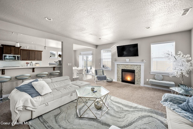 carpeted living room with a tile fireplace and a textured ceiling