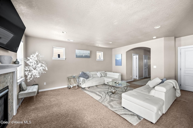 carpeted living room featuring a fireplace and a textured ceiling