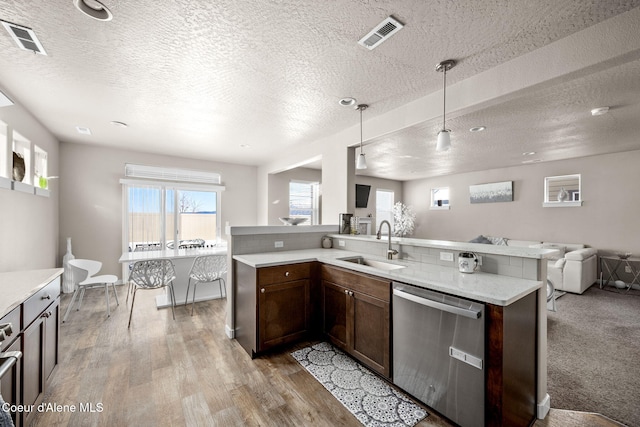 kitchen featuring sink, hanging light fixtures, stainless steel appliances, light stone countertops, and light wood-type flooring