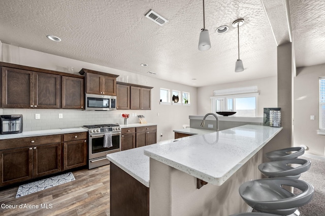 kitchen featuring stainless steel appliances, a kitchen breakfast bar, light stone countertops, and kitchen peninsula