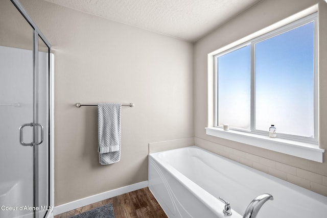 bathroom featuring hardwood / wood-style flooring, shower with separate bathtub, and a textured ceiling