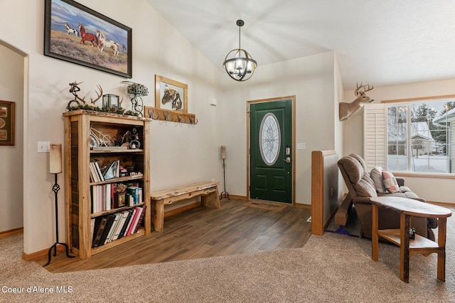 foyer with dark colored carpet, lofted ceiling, and a chandelier