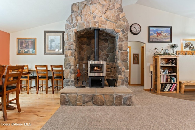 living room featuring vaulted ceiling, hardwood / wood-style floors, and a wood stove