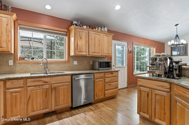 kitchen featuring appliances with stainless steel finishes, sink, decorative backsplash, hanging light fixtures, and light stone counters