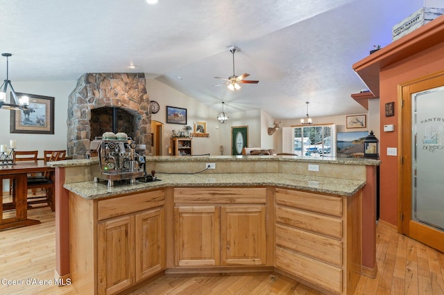 kitchen with lofted ceiling, light stone countertops, hanging light fixtures, and light hardwood / wood-style flooring