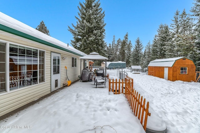 yard layered in snow featuring a gazebo and a shed