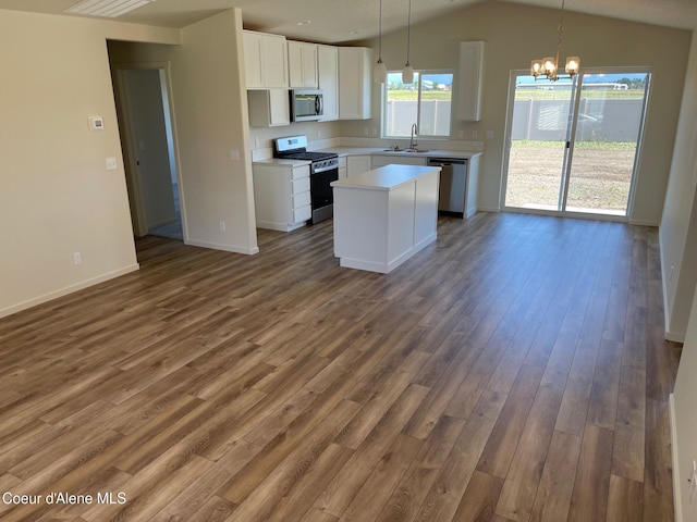 kitchen with stainless steel appliances, light countertops, white cabinetry, vaulted ceiling, and wood finished floors