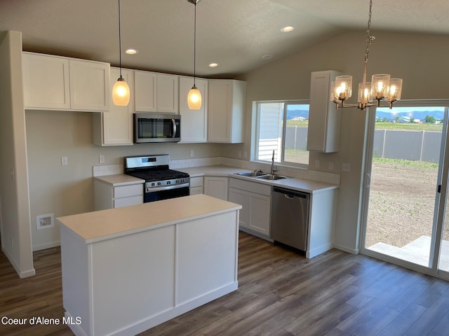 kitchen featuring a center island, appliances with stainless steel finishes, white cabinetry, vaulted ceiling, and a sink