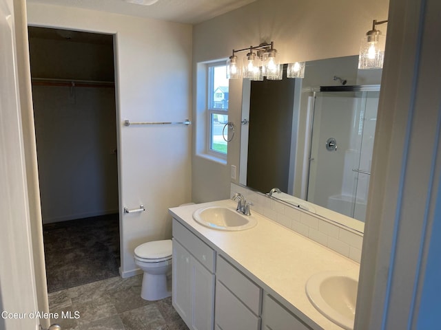 full bath with toilet, a sink, a shower stall, double vanity, and a walk in closet