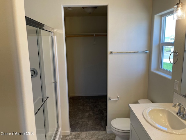 full bathroom featuring toilet, a stall shower, a walk in closet, and vanity