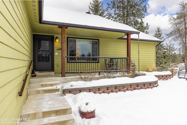 snow covered property entrance featuring a porch