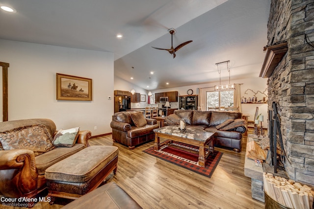 living room with a fireplace, vaulted ceiling, light hardwood / wood-style floors, and ceiling fan