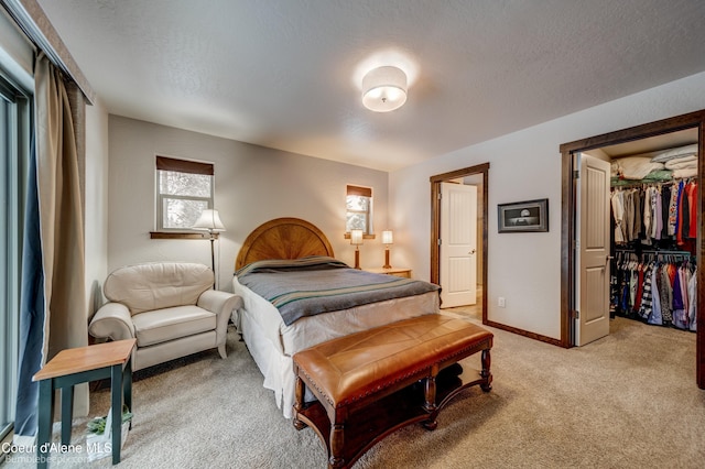 bedroom featuring a closet, a spacious closet, light carpet, and a textured ceiling