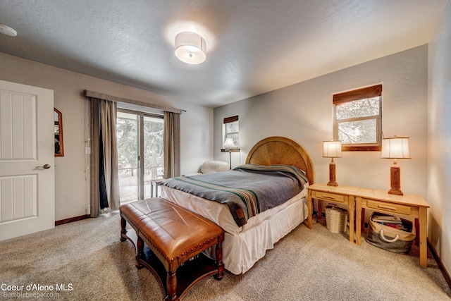 bedroom featuring light colored carpet, access to exterior, and a textured ceiling